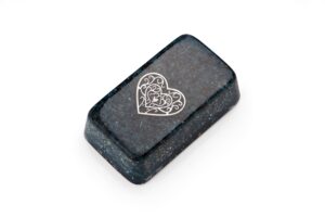 Ladrillo orgonite rectangular gris oscuro-negro con diseño de corazón blanco con espirales decorativas, fotografiado en ángulo