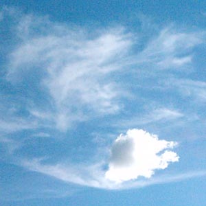 Blue sky with wispy white clouds and one prominent puffy white cloud formation