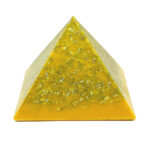Pyramide orgonite jaune-orange avec copeaux métalliques incrustés partout, vue de face sur fond blanc