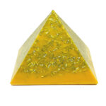 Pyramide orgonite jaune translucide avec paillettes métalliques incrustées, photographiée sur fond blanc