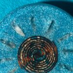 Runde dunkle Glasspiralteller mit Metallpartikeln auf blauer strukturierter Oberfläche mit klaren Kristallspitzen am Rand