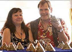 Two people smiling at camera, sitting at table with pyramid-shaped objects arranged in front of them