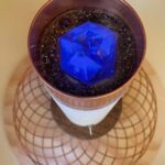 Zylindrischer orgonite-Stab mit weißer Basis, Kupferrand, dunklem Harz oben mit hellblauem Kristallwürfel, von oben betrachtet