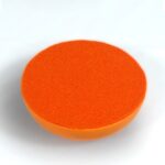 Runde orange orgonite Scheibe mit strukturierter Oberfläche, von oben in leichtem Winkel auf weißem Hintergrund