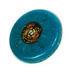 Runde blaue orgonite Scheibe mit goldener Spiralspule in der Mitte, von oben auf weißem Hintergrund