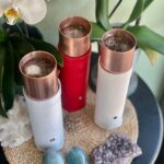 Trois baguettes orgonite à pointes cuivre avec étuis cuir blanc et rouge, glaçons dedans, sur natte tressée avec cristaux