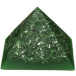 Grüne durchscheinende Pyramide mit kleinen grünen Kristallsplittern und Metallfragmenten, von vorne betrachtet