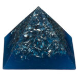 Pyramide orgonite bleue translucide avec copeaux métalliques et cristaux intégrés, photographiée sur fond blanc