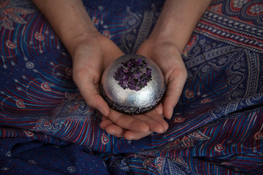 Hands holding orgonite sphere