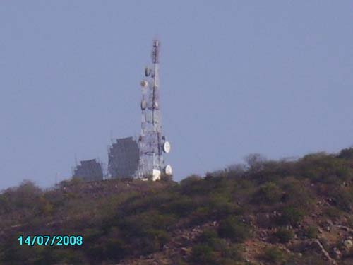 Communication tower with satellite dishes on rocky hilltop against clear sky, dated 14/07/2008