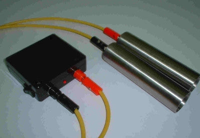 Black electronic device with yellow cables connected to two metallic cylindrical objects against white background