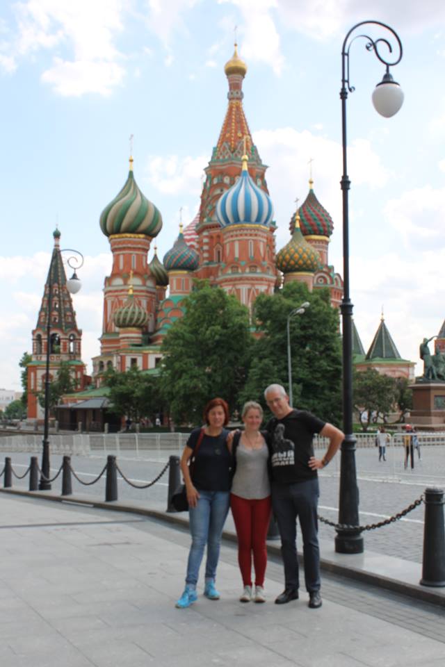Three people pose together in front of St. Basil's Cathedral with colorful onion domes in Moscow's Red Square