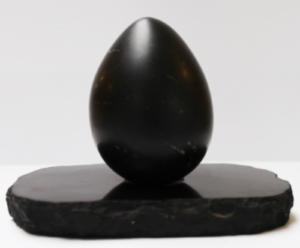 Black polished egg-shaped stone object sitting on a dark flat oval base against white background